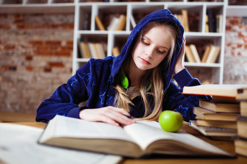 Teenage girl in blue hood reads in library